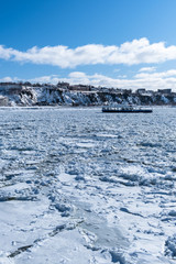 Ferry boat crossing the river covered with ice