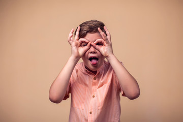 A portrait of kid boy showing okay gesture and tongue. Children and emotions concept