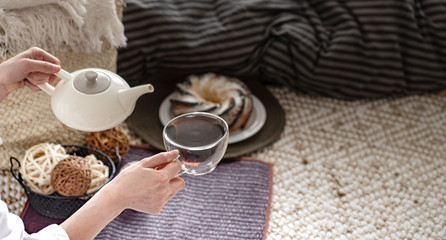 Hands of a young woman pour tea from a teapot.