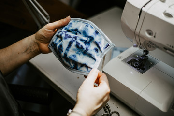 Woman sews homemade face mask because of the protective mask requirement during corona virus pandemic.