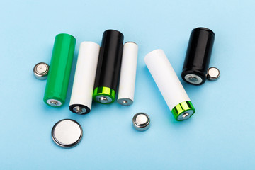 many new and used batteries of different shapes, AA, round batteries on a blue background.