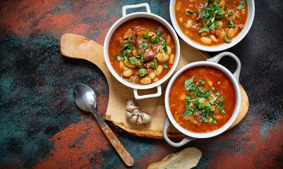Bean soup with meat and vegetables served on a rustic board with garlic. Traditional Balkan soup or...