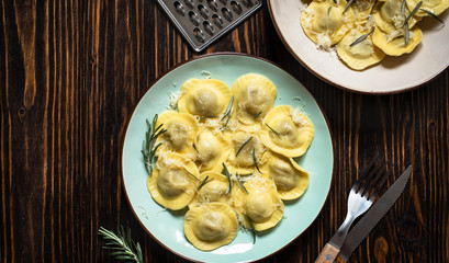 Traditional italian ravioli with rosemary and parmesan served on a rustic wooden table. Italian pasta. Top view, copy space