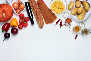 Groceries on white background: bell peppers, dried chili, oregano, curry, allspice, onions, pasta, bottle of olive oil, spaghetti, baguette, tomatoes, pumpkin, potatoes at the top of the frame