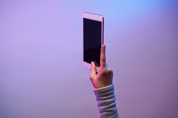 Close-up of man's hands with smartphone and blank black screen on blank purple background.