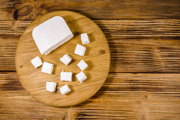 Cutting board with chopped feta cheese on a wooden table. Top view