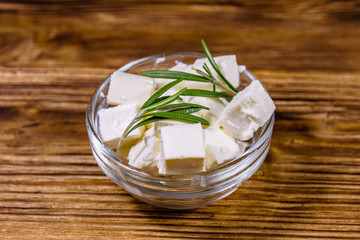 Chopped feta cheese and rosemary in glass bowl on a wooden table