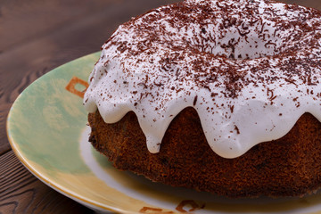 Homemade Traditional English Easter cake covered with white icing and chocolate parsley on a ceramic plate on a white wooden table in a rustic style.