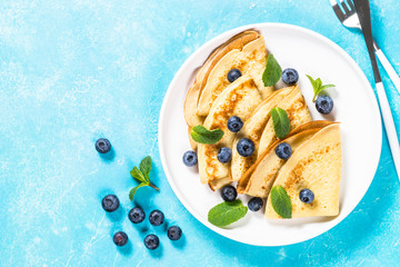 Crepes with blueberries at white table.