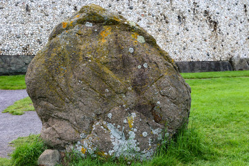 A large weathered standing stone in front of Newgrange megalithic passage tomb in the Boyne Valley,...