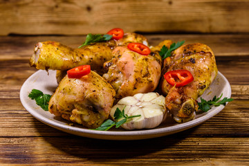Baked chicken legs with parsley, garlic and sliced red hot pepper in a plate