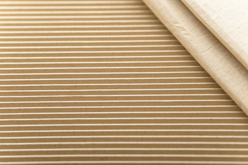 Carton or cardboard packing material. Texture of corrugated paper sheets made from cellulose. Supplies for creating boxes and packaging. Pasteboard background. Natural brown cardboard surface.