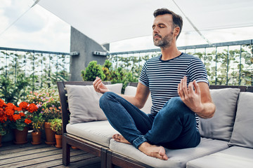 man meditating on terrace during sunny day