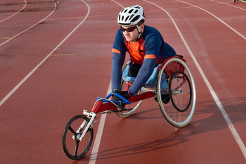 Paraplegic sportsman in racing wheelchair warming up before competition