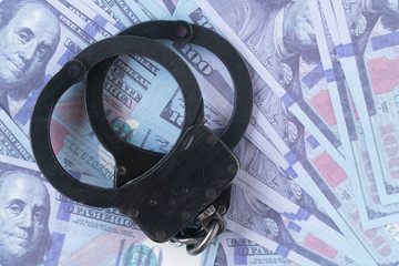 handcuffs against the background of hundred-dollar bills