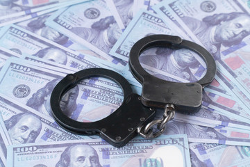 close up handcuffs against the background of hundred-dollar bills