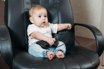 small child sits in a chair and holds the joystick from the game console.