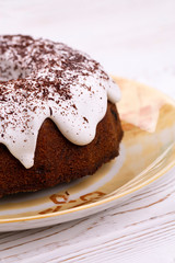 Homemade Traditional English Easter cake covered with white icing and chocolate parsley on a ceramic plate on a white wooden table in a rustic style.