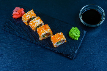 Sushi roll philadelphia with salmon, rice, cheese, cucumber, avocado and caviar on a slate board. Japanese food