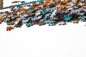 Scattered jigsaw puzzle pieces in natural colors. Lying on white table. Copy space. Concept of connect elements.