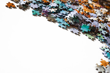 Scattered jigsaw puzzle pieces in natural colors. Lying on white table with copy space. Concept of messy and connection elements.