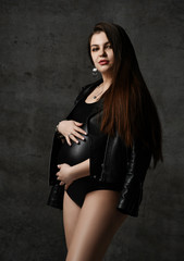 Young beautiful slim pregnant woman with long hair in posing on black background. Pregnancy motherhood, new born life expectation
