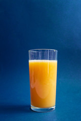 glass of fresh orange juice against blue background with empty space for text, healthy lifestyle concept