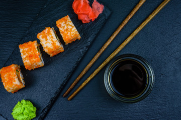 Sushi roll philadelphia with salmon, rice, cheese, cucumber, avocado and caviar on a slate board. Japanese food. Top view