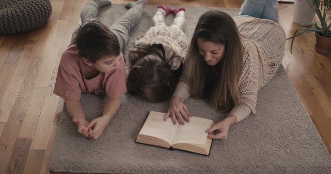 Mother sleepy daughter and son loving family together reading a book stay at home virus pandemic outbreak high angle