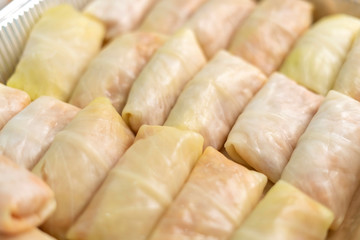 Detail of a tray full of fresh rolled stuffed cabbage, which are preparing to bake.