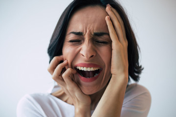 Close-up photo of a woman with bipolar disorder who is screaming and crying because of her...