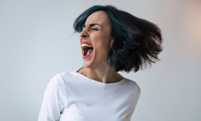 Close-up photo of a woman with bipolar disorder who is screaming and crying because of her...