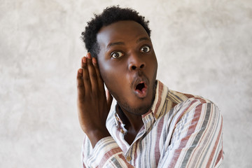 Emotional curious young Afro American man with mouth gaped open expressing surprise and full...