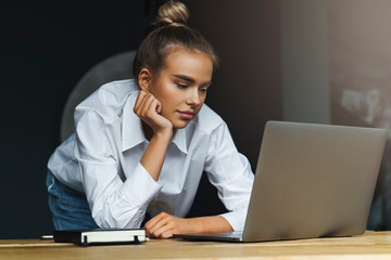 Beautiful young business woman working remotely from home. Student preparing for seminar, writing notes in copybook