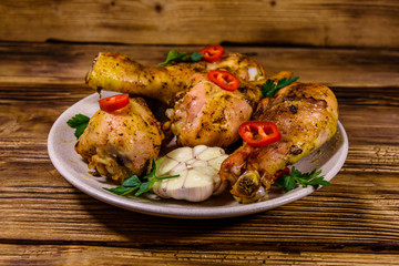 Baked chicken legs with parsley, garlic and sliced red hot pepper in a plate