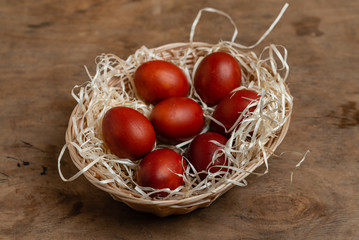 Fototapeta na wymiar red easter eggs in wicker basket on wooden background