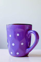 Purple cup with polka dots on a light background