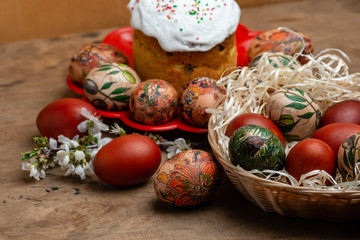 Easter cake and easter eggs in wicker basket with blooming twig on wooden background