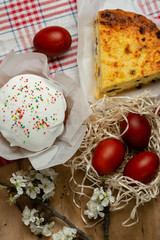 Easter cake, cheese casserole and Easter eggs in a wicker basket with a flowering branch on a wooden background