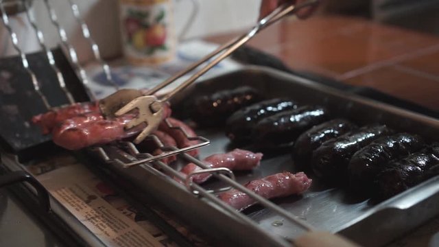 Grilled white sausages served with tongs on a metal tray
