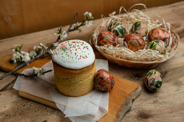Easter cake, and Easter eggs in a wicker basket with a flowering branch on a wooden background
