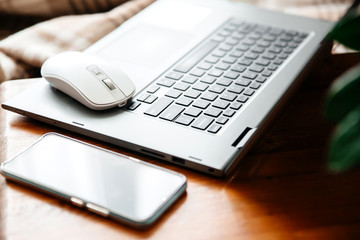 Laptop keyboard, computer mouse, smartphone top view. Checkered plaid in the background. Home office. Working remotely. Work from home. Cozy office at home