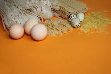 rice noodles all kinds of pasta and pasta with chicken and quail eggs on an orange background