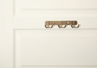 White door with empty metal clothes hooks