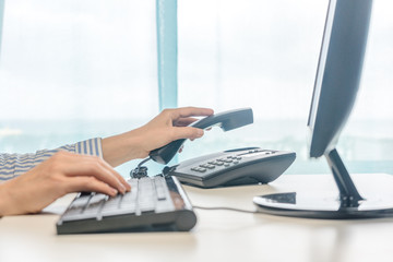 Female working, hands using computer telephone, closeup.