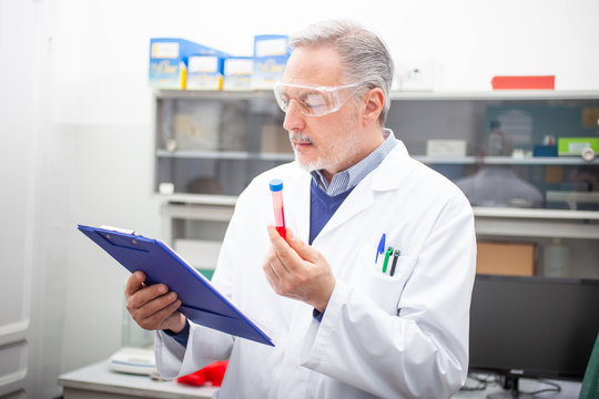 Medical sientist researcher looking at a blood tube, coronavirus blood test