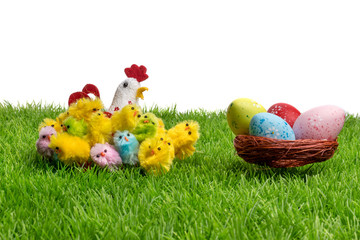 Fototapeta na wymiar Decorative easter chickens, eggs in a nest and hen on plastic grass, forming a festive scene. Isolated on white background.