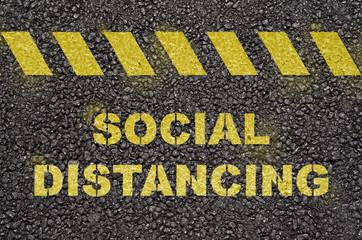 Social distancing text on the black asphalt