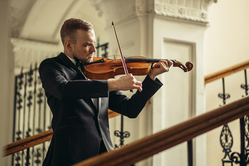 young caucasian talented violinist play violin, handsome guy in formal suit perform classical...