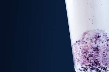 close-up of a milkshake with blueberries in a glass on a blue background